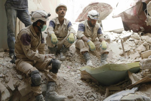 Civil Defence members sit on rubble at a site hit by what activists said was a barrel bomb dropped by forces loyal to Syria's President Bashar al-Assad in Aleppo's Bustan al-Qasr neighborhood. (Hosam Katan/Reuters)